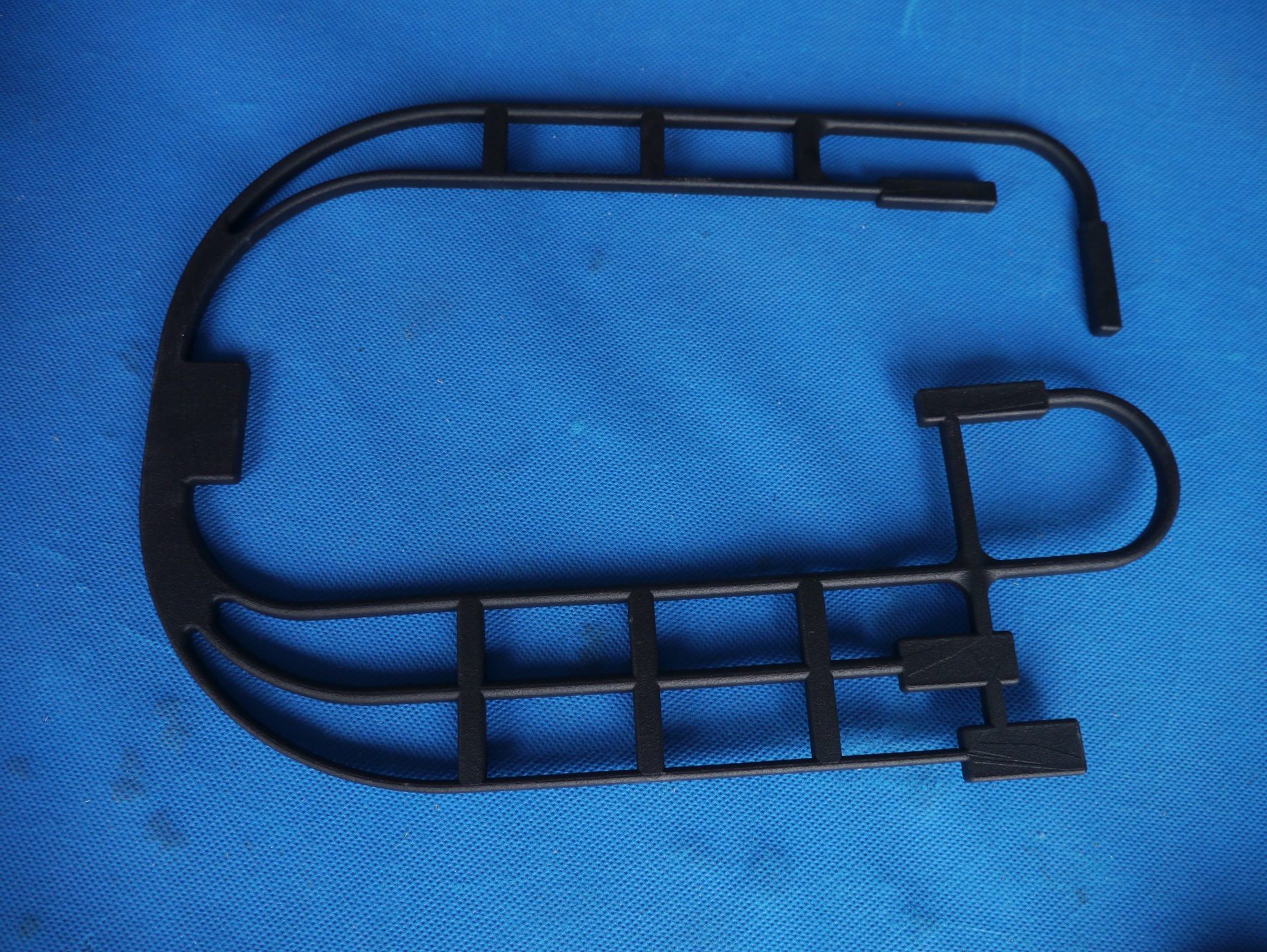 Black SLS printed functional frame part on a blue work surface